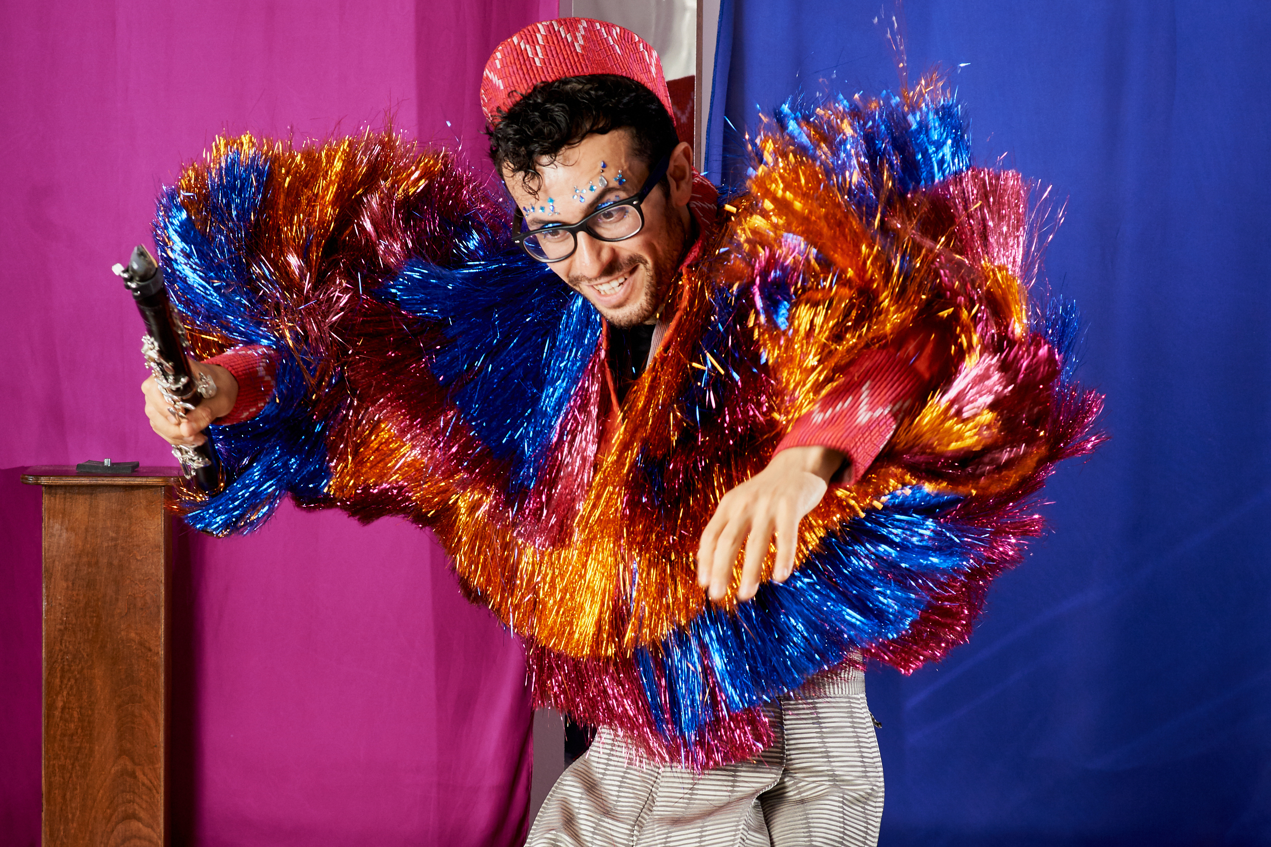 Photograph of a man with shiny blue, orange and pink fringe jacket