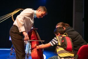 A child in the audience touching a cello