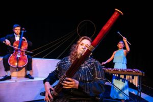 Three performers playing instruments on stage