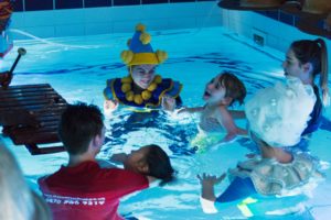 Child bring supported in the water with performers in costume