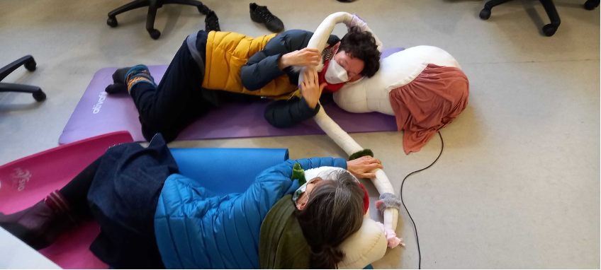 Tilde listening device being tested at Oily Cart headquarters. Two people are lying down using each part of Tilde as pillows.