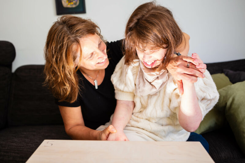 A young person's face is illuminated by light from a drawer they have opened, though we can't see what is inside. The adult smiles, looking at their face.
