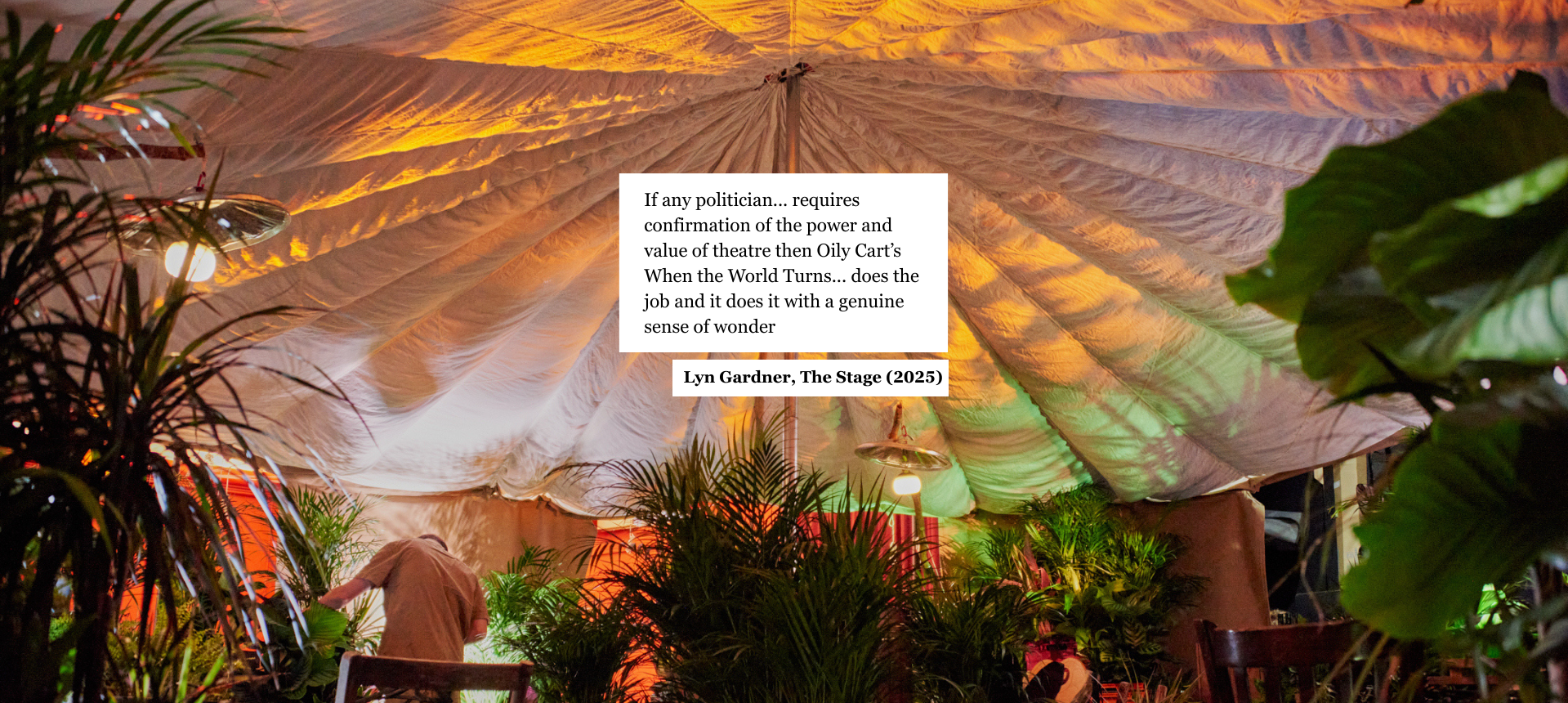 Quote from an article, overlaid on a photo of the When the World Turns set. The text reads: "If any politician... requires confirmation of the power and value of theatre then Oily Cart’s When the World Turns... does the job and it does it with a genuine sense of wonder". Lyn Gardner, The Stage (2025)